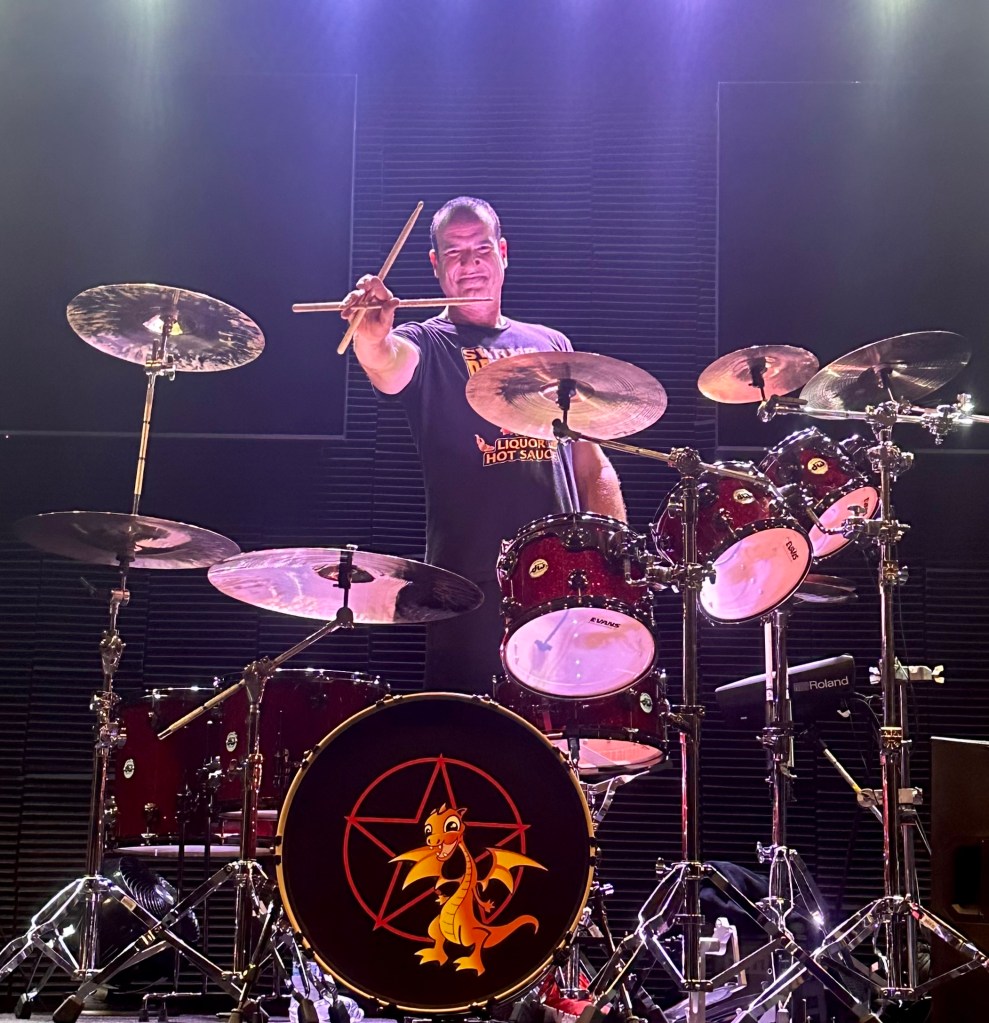 Matt Beeson stands behind drumset under stage lights