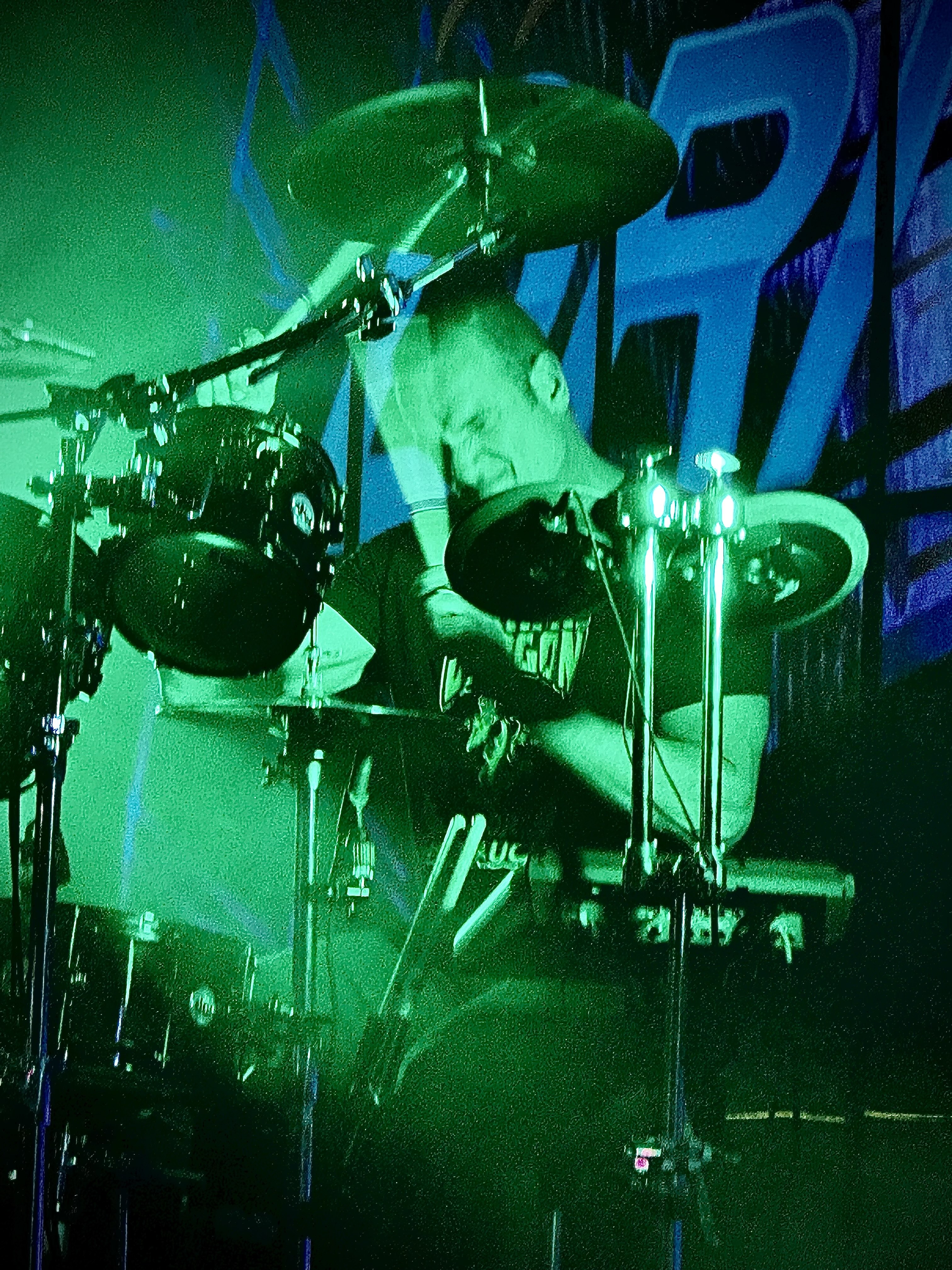 Drenched in green stage light, Matt Beeson plays the drums hard